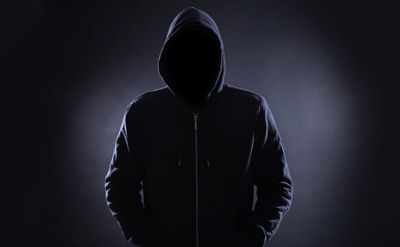 Anonymous man in hood on black background