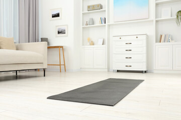 Grey yoga mat on floor in room