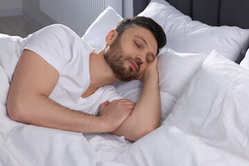 Fototapeta na wymiar Handsome man sleeping in soft bed at home