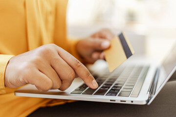 Closeup of business woman hand using laptop holding credit card shopping online, ordering food, selective focus. Successful freelancer receive payment. Technology concept