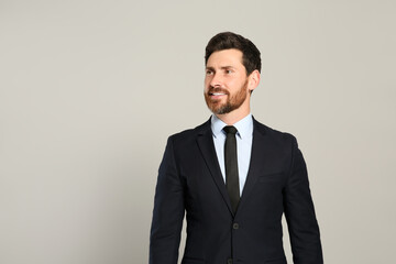 Handsome real estate agent in nice suit on grey background, space for text