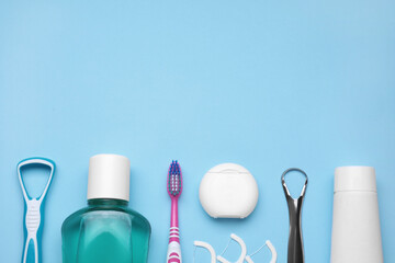 Tongue cleaners and other oral care products on light blue background, flat lay. Space for text