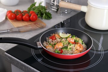 Tasty rice with shrimps and vegetables in frying pan on induction stove