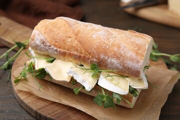 Tasty sandwich with brie cheese on wooden table, closeup