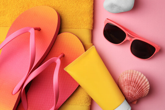 Flat lay composition with sunscreen and beach accessories on pink background
