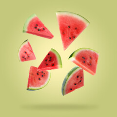 Slices of fresh juicy watermelon falling on yellow green background