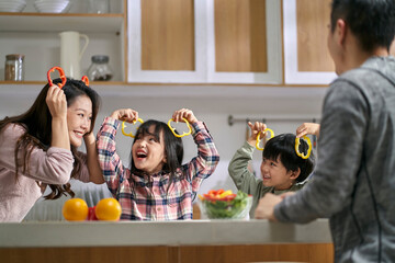 young asian family with two children having a good time in kitchen at home