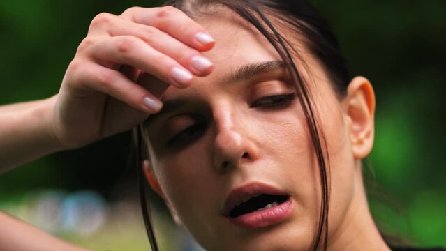 Beautiful Athletic Woman Wipes Sweat from Her Forehead with a Hand, Looks into Camera. She's Tired after Intensive Cross Fitness Exercise