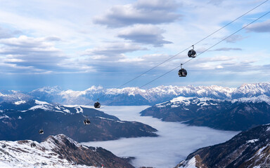 Cable car in the Austrian Alps in winter near Kaprun. Behind the snow-covered peaks, illuminated by...