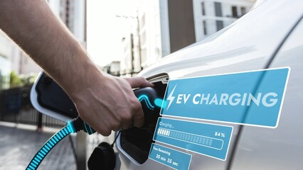 Hand insert EV charger and recharge electric car from charging station displaying futuristic...