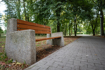 Samotna ławka stojąca w parku przy dróżce w otoczeniu zieleni podmiejskiego rejonu zachodniej...