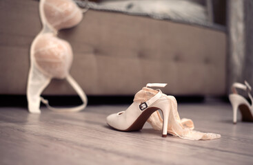 Female underwear thrown on the floor with a high heeled shoes in a white room near the bed. Sex concept.