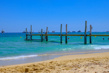Obraz premium Crystal clear blue water and boats on legendary Pampelonne beach near Saint-Tropez, summer vacation on white sandy beach of French Riviera, France