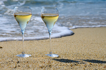 Summer time in Provence, two glasses of cold champagne cremant sparkling wine on sandy beach near Saint-Tropez in sunny day, Var department, France