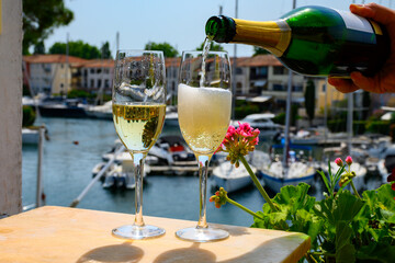 Drinking of French brut champagne sparkling wine in glasses, club party in yacht harbour of Port Grimaud near Saint-Tropez, French Riviera vacation, France