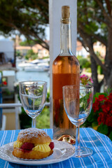 Wine and cake of French Riviera, glasses of cold rose Cote de Provence wine and Tarte Tropezienne cake in yacht harbour of Port Grimaud, summer vacation  in Provence, France.