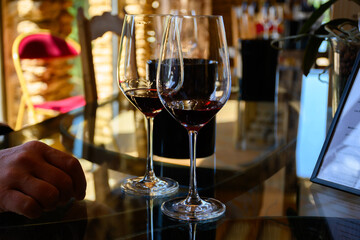 Tasting of red dry wine in Chateauneuf-du-Pape wine making village in France with green vineyards on large pebbles galets and sandstone clay soil