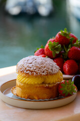 Tarte tropezienne or La Tarte de Saint-Tropez - dessert pastry consisting of filled brioche with cream and fresh berries served outdoor with fresh ripe strawberry