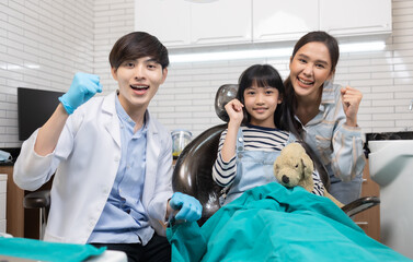 Children's dentistry for healthy teeth .Close-up  happy little child asian girl smiles looking at camera, sitting in dentist's chair, receiving dental.