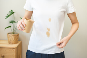 Cloth stain, disappointment asian young woman clumsy with hot coffee, tea stains on shirt, hand...