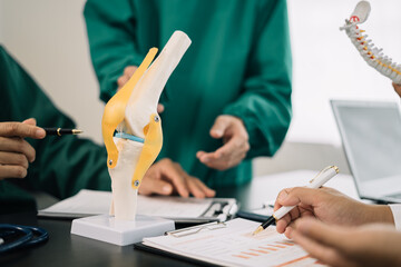 serious doctors team are analyzing fracture knee model showing the process of osteoarthritis patients and knee arthroplasty. - obrazy, fototapety, plakaty