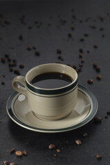 Coffee cup and coffee beans on black background. Vintage style