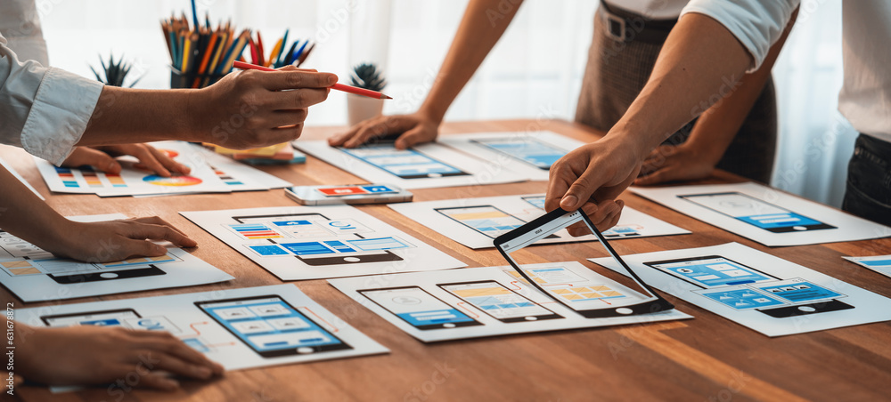 Poster Panorama shot of front-end developer team brainstorming UI and UX designs for mobile app on paper wireframe interface. User interface development team planning for user-friendly UI design. Scrutinize