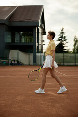 Young woman tennis player walking among professional court