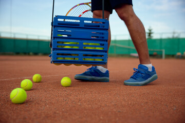 Closeup view of tennis player picking up scattered balls on field