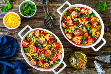 Bread casserole with mozzarella cheese, tomatoes and scrambled eggs on wooden table
