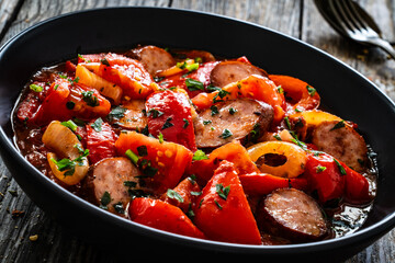 Delicious letcho - vegetables with sausages on wooden table
