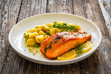 Seared salmon steak with gnocchi and lemon slices served on wooden table

