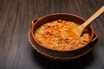 Authentic mexican chicken tinga, typical mexican food prepared in a clay pot on a wooden table.