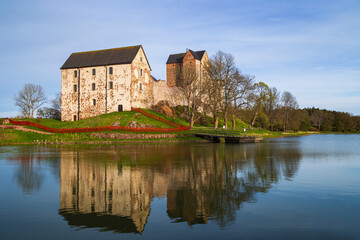 Naklejka na ściany i meble Medieval Kastelholm Castle and its reflections on a calm river in Åland Islands, Finland, on a sunny day in the summer.