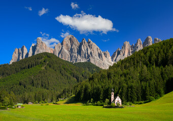 St Johann Church with landscape view of dolomites mountain peaks and blue sky, Santa Magdalena alpine village, Italy - 631702094