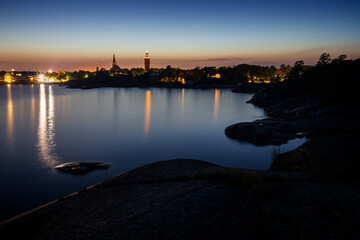 Fototapeta premium Rocky coastline and shoreline cliffs at Puistovuori nature park and cityscape in Hanko, Finland, at dusk in the summer.