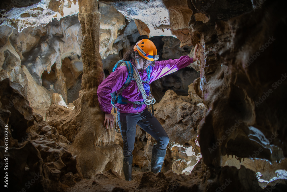 Wall mural young woman spelunking inside a cave. feminism concept. concept of women's sport.