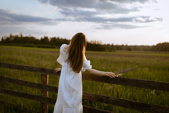 A young woman in a white sundress in the countryside.