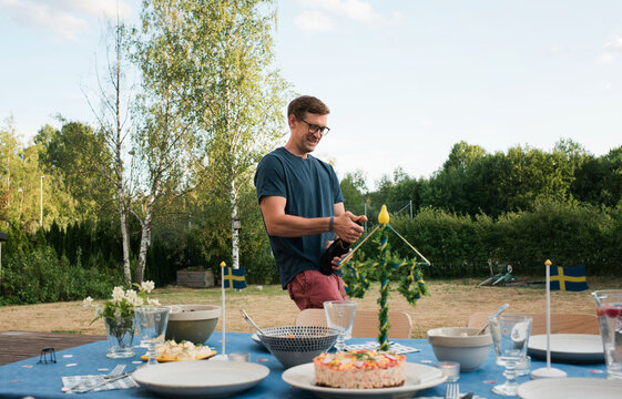 man popping the champagne cork at Swedish midsummer party