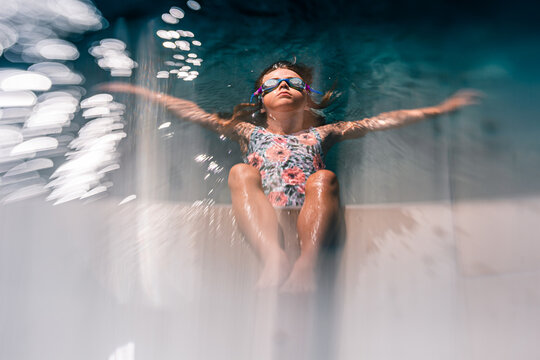 7 years old girl relaxing in the pool during summer on a sunny day