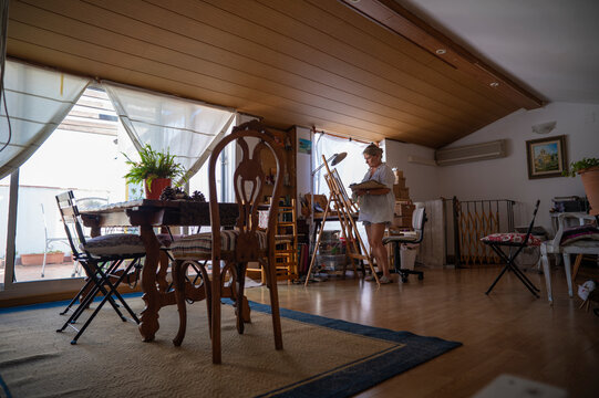 General view of a mature woman painting in her studio.