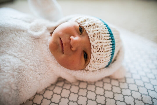 Side view of cute baby dressed in white toque and cozy onesie