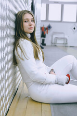 Girl in white sport wear with a sword on training. Fencing exercises