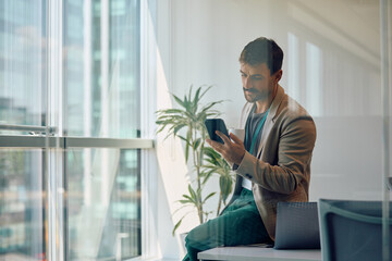 Businessman texting on cell phone during his coffee break in office.