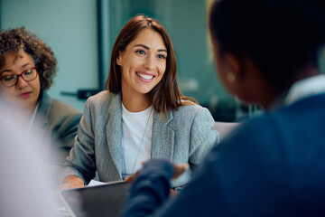 Happy entrepreneur talking to her coworkers on business meeting in office.
