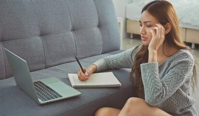 Asian woman sitting on floor holding pen, writing, working from home, noting, writing down, housewife planning week, writing to-do list, student preparing university admissions.