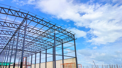 Metal roof beam and columns of warehouse building structure in construction site area against...