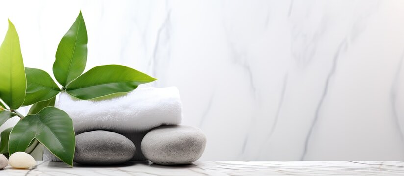Spa background concept with white stones, towel, and green plant leaves on a marble background. Suitable for body care, beauty treatments, and spa or wellness centers. Includes copy space.