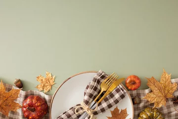  Gorgeous fall table arrangement.Top view photo of plate, cutlery, checkered napkin, tablecloth, raw pumpkins, maple leaves on olive background with empty space for promo or text © Goncharuk film