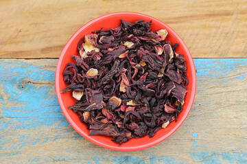 Dried Hibiscus flowers in a plate on wooden background top view 